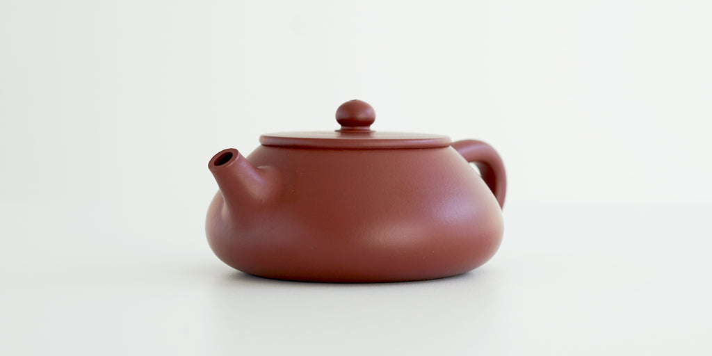 Front view of a terracotta-colored yixing pot highlighting the stout spout.