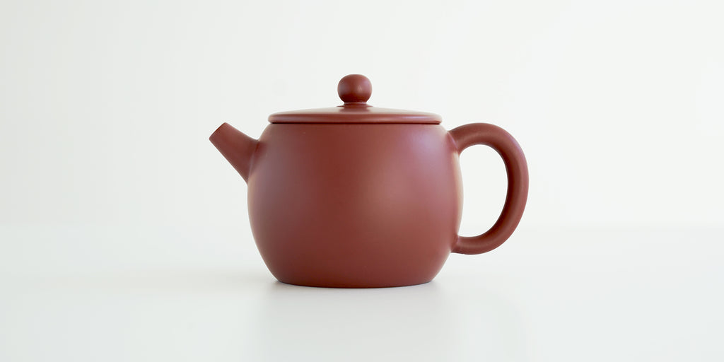 Side view of a terracotta-colored yixing pot, highlighting the oval shape.