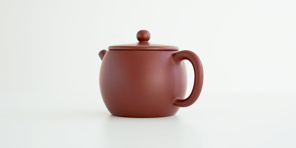Rear view of a terracotta-colored yixing pot, highlighting the thin handle.