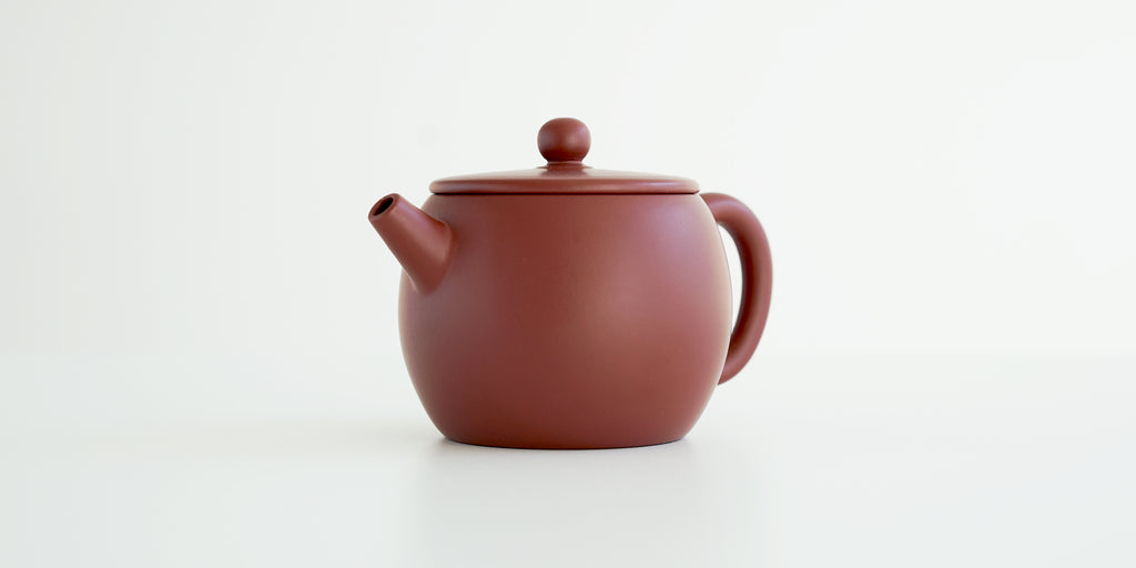 Front view of a terracotta-colored yixing pot highlighting the narrow spout.