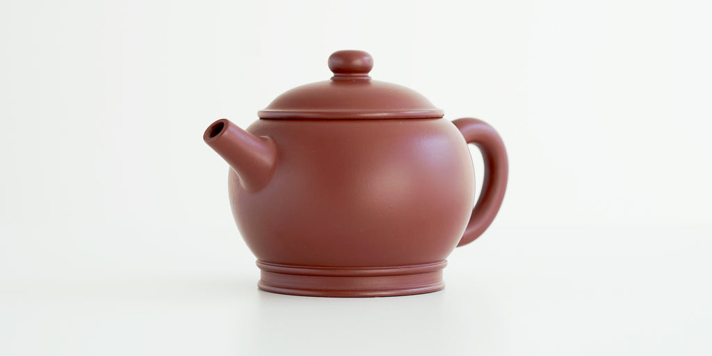 Front view of a terracotta-colored yixing pot highlighting the narrow spout.