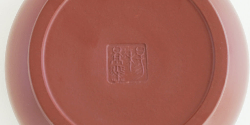 The bottom of a terracotta-colored yixing teapot. A maker’s mark is stamped into the base.