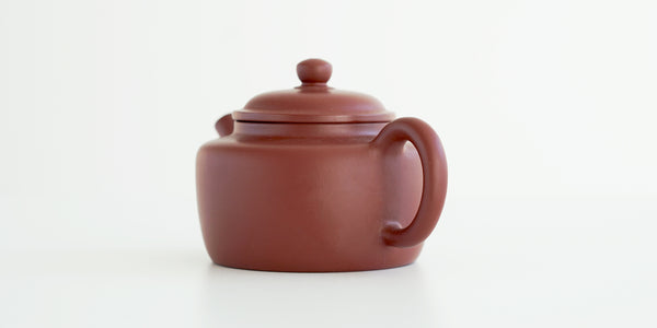 Rear view of a terracotta-colored yixing pot, highlighting the oval handle.