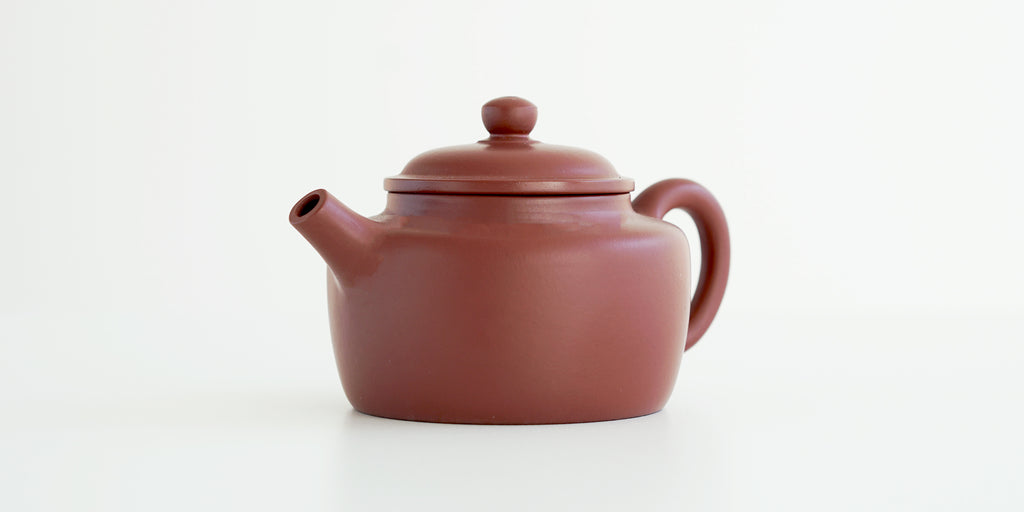 Front view of a terracotta-colored yixing pot highlighting the cylindrical spout.