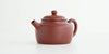 Front view of a terracotta-colored yixing pot highlighting the cylindrical spout.