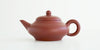 Side view of a terracotta-colored yixing pot, highlighting the smooth and flowing shape.
