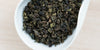 A white dish containing dry Tieguanyin tea leaves.