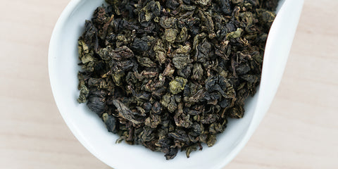 A white dish containing dry Tieguanyin tea leaves.