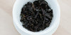 A top-down photo of brewed Wuyi oolong tea leaves in a gaiwan.