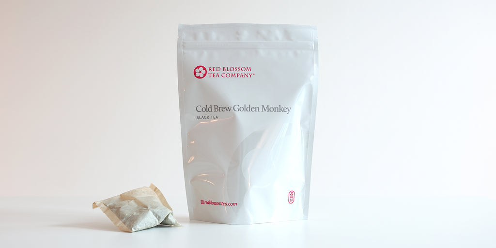 A large teabag filled with black tea next to a package of Cold Brew Golden Monkey