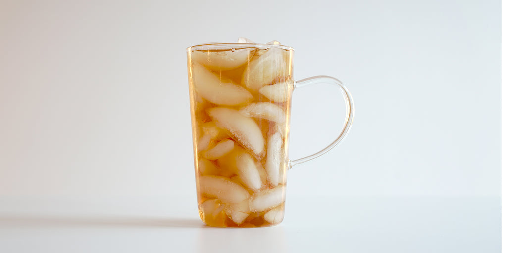 A glass cup filled with ice and wuyi oolong tea on a white background.