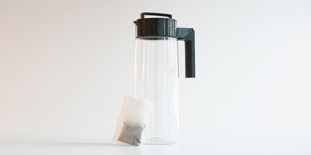 A plastic pitcher with a sachet of tea leaning against it.