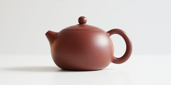 Side view of a terracotta-colored yixing pot, highlighting the bulbous shape.