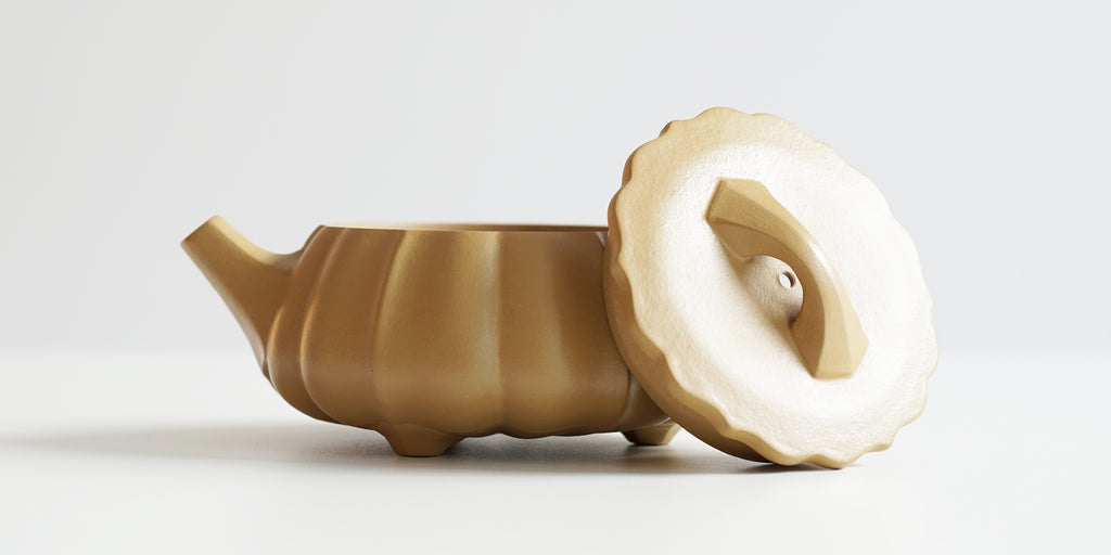 Side view of a terracotta-colored yixing teapot. The lid is facing the camera, resting against the handle.