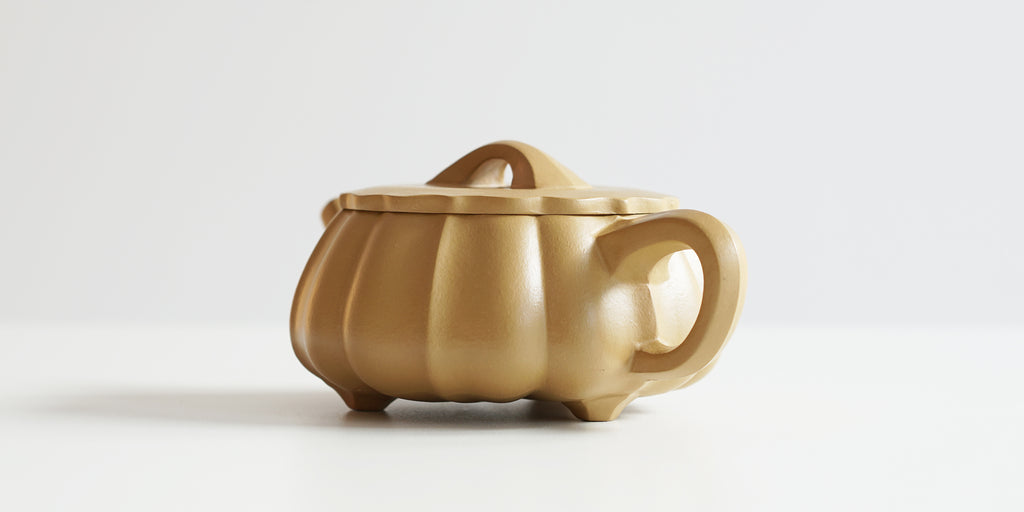 Rear view of a terracotta-colored yixing pot, highlighting the hexagonal handle.