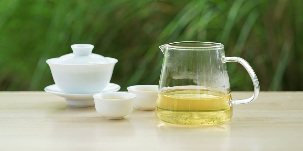 From left to right, a gaiwan, two teacups, and a glass server. The teacups and server have Formosa oolong tea in them.