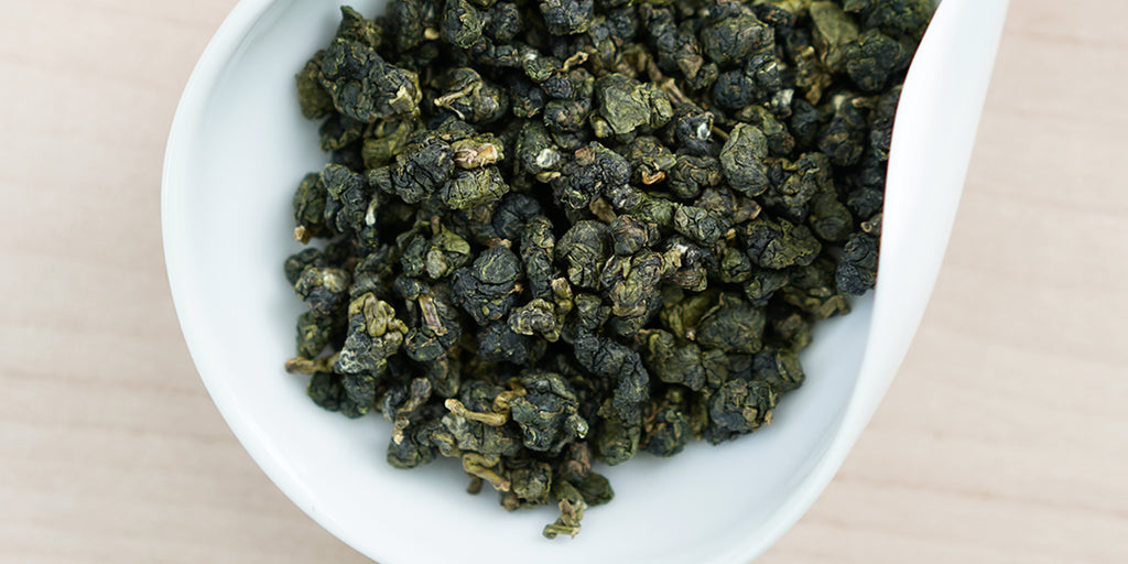 A white dish containing dry Formosa oolong tea leaves.