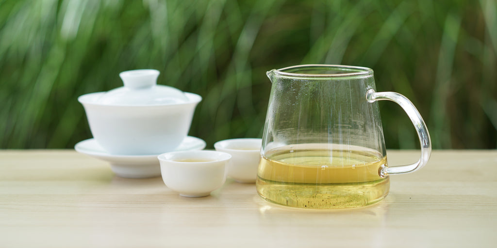 From left to right, a gaiwan, two teacups, and a glass server. The teacups and server have Formosa oolong tea in them.