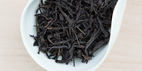 A white dish containing dry Phoenix oolong tea leaves.