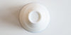Bottom of a white porcelain teacup, with a Red Blossom Tea Company logo etched into the base.