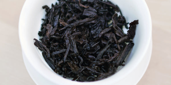 A top-down photo of brewed pu-erh tea leaves in a gaiwan.