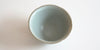 Top down view of a blue-green celadon teacup. The lip has slight indentations from the grooves on the outside.