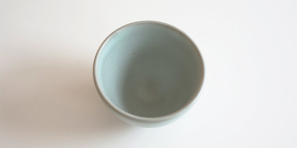 Top down view of a blue-green celadon teacup, with a grayish rim.
