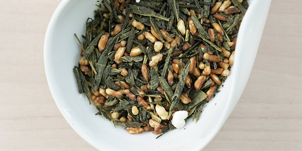 A white dish containing dry green tea leaves and toasted rice.