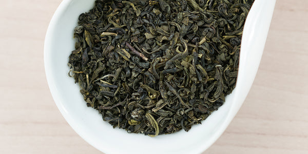 A white dish containing dry jasmine tea leaves.