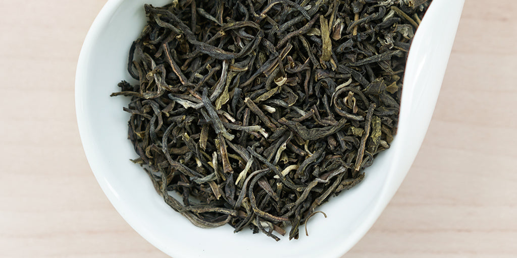A white dish containing dry Formosa oolong tea leaves.