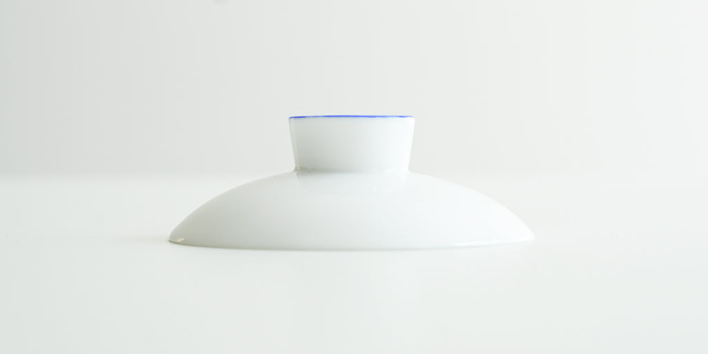 A white porcelain lid, with a blue ring around the top of the handle.