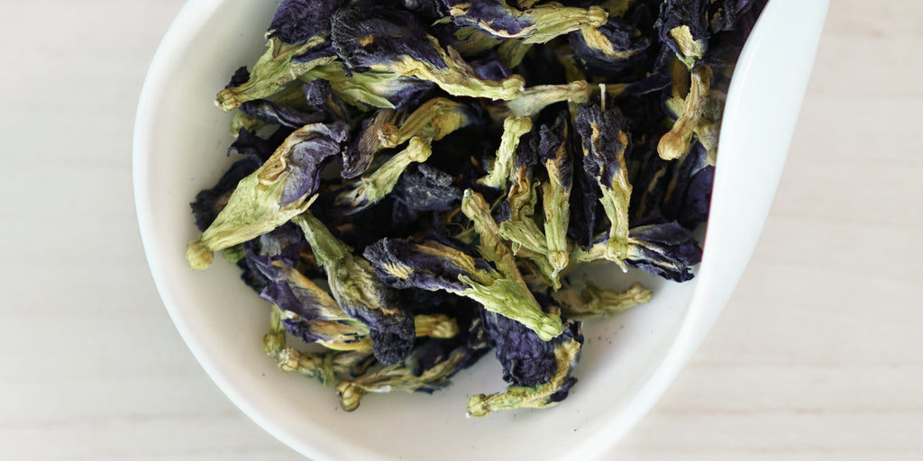 A white dish containing dry butterfly pea flowers.