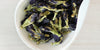 A white dish containing dry butterfly pea flowers.