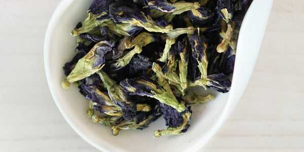 A white dish containing dry butterfly pea flowers.