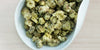 A white dish containing dry chrysanthemum buds.