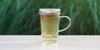 A glass cup with elderflower brewing in the nested glass infuser.