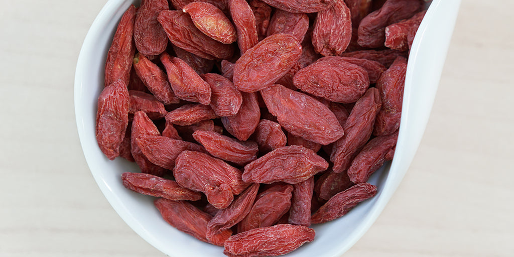 A white dish containing dry goji berries.