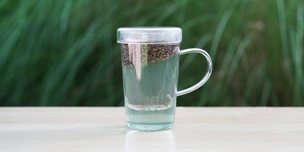 A glass cup with lavender brewing in the nested glass infuser.