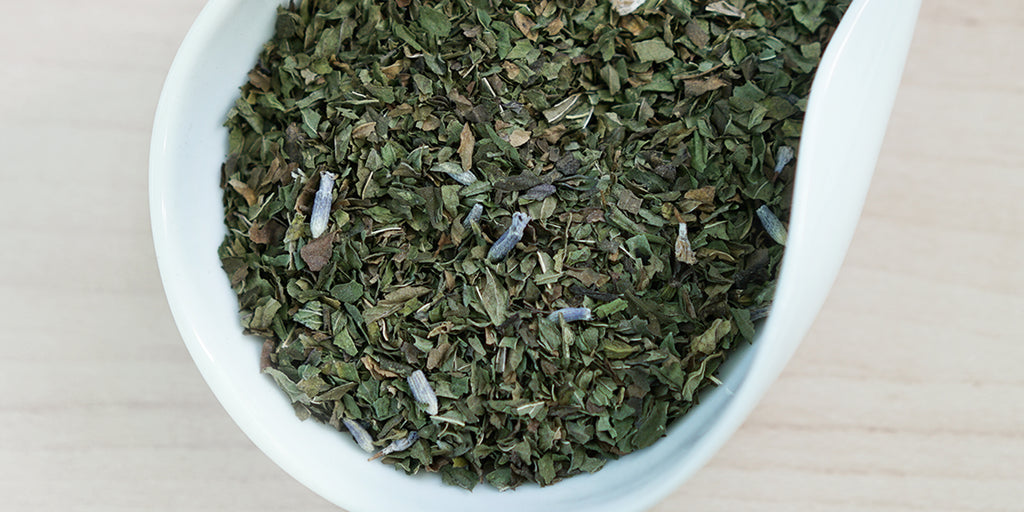 A white dish containing dry peppermint leaves and lavender flowers.