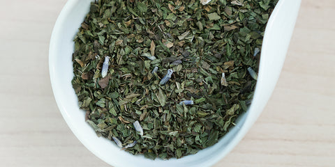 A white dish containing dry peppermint leaves and lavender flowers.