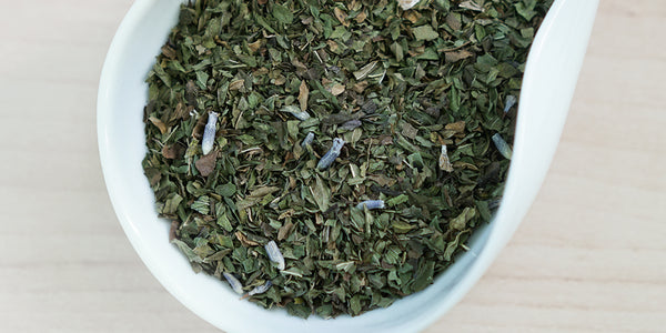 A white dish containing dry peppermint leaves and lavender flowers.