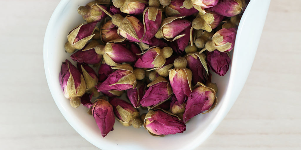 A white dish containing dry rose buds.