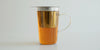 A glass cup of tea with a steel infuser in it brewing tea.