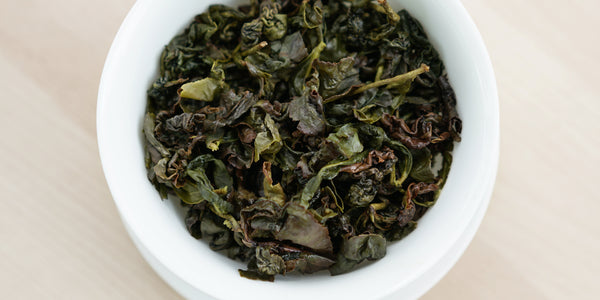 A top-down photo of brewed Formosa oolong tea leaves in a gaiwan.