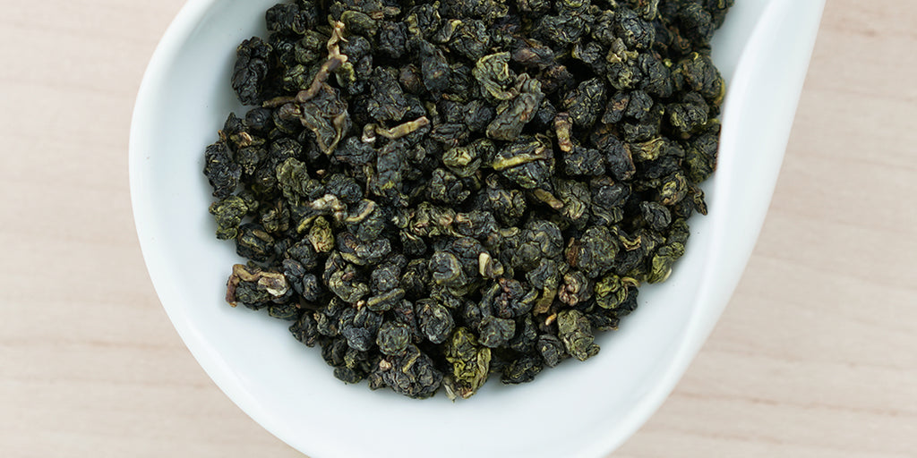 A white dish containing dry Formosa oolong tea leaves.