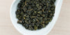 A white dish containing dry Formosa oolong tea leaves.