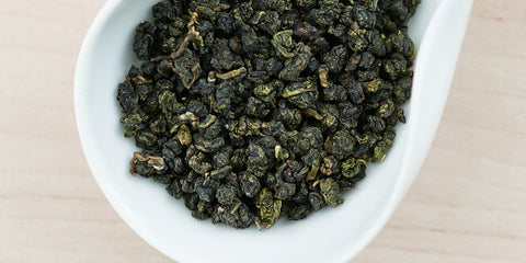 A white dish containing dry Formosa oolong tea leaves.