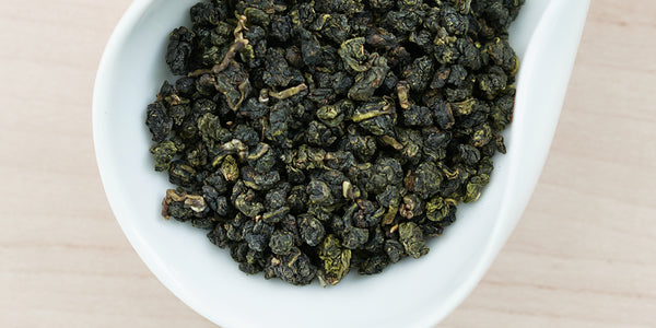 A white dish containing dry Formosa oolong tea leaves.