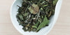 A white dish containing dry white tea leaves.
