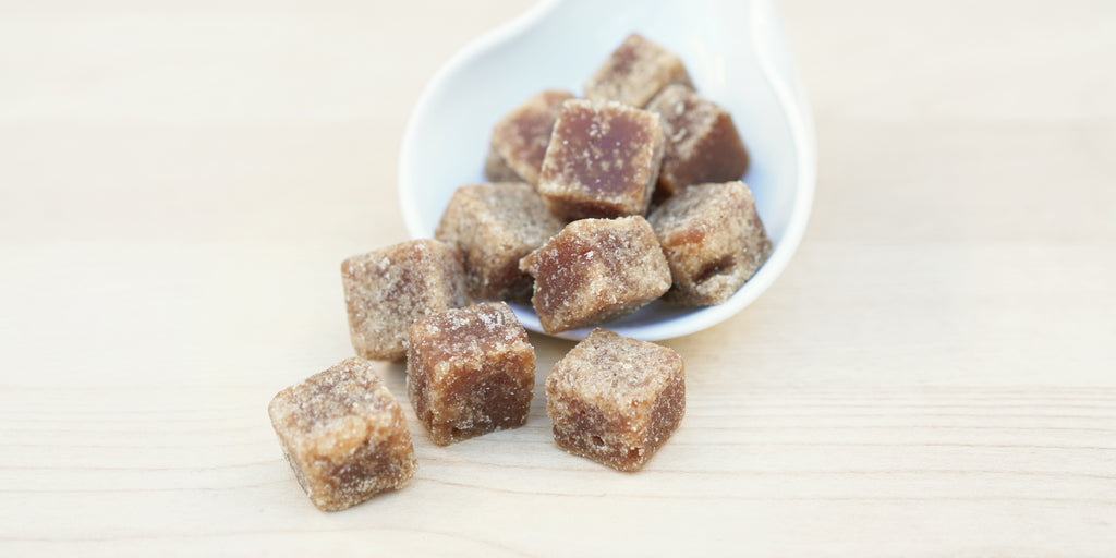 A white dish with cubes of winter melon sugar overflowing from it.
